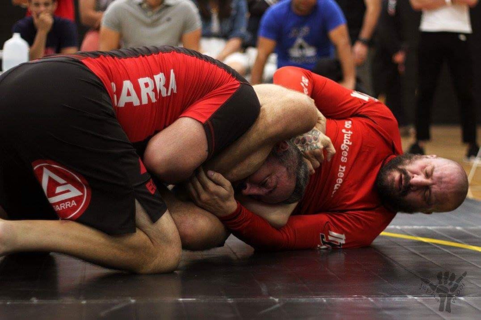 Sonny Parlin in a red rashguard locked up in a scramble with a Gracie Barra competitor