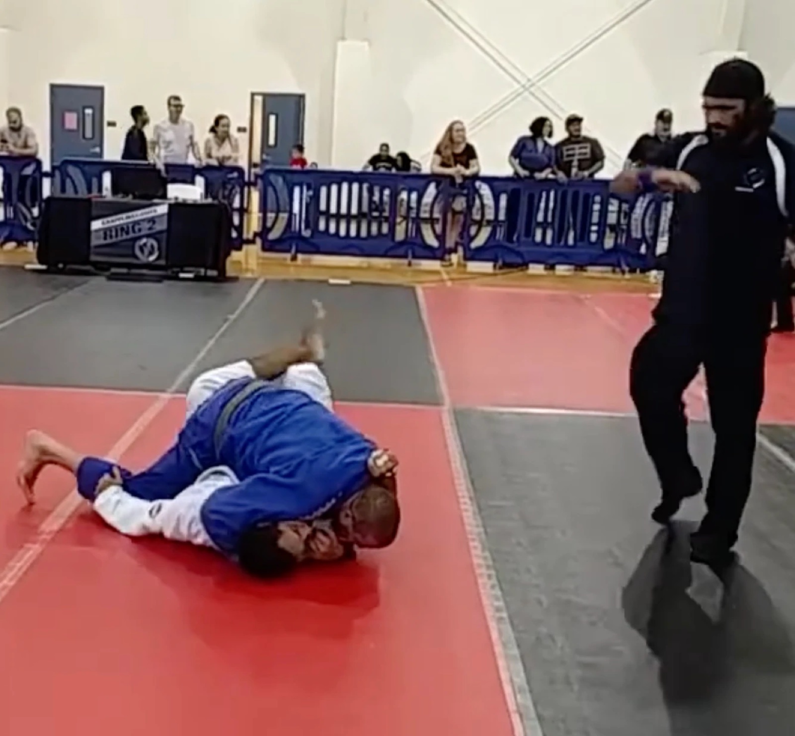 Sonny Parlin in a blue gi pinning an opponent on a red mat at a gi tournament
