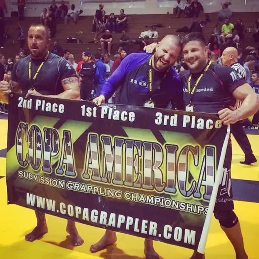 Sonny Parlin in first place holding the Copa America Submission Grappling Championships banner with the other medalists