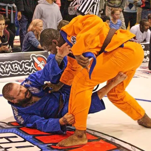 Sonny Parlin in a blue gi playing guard against an opponent in an orange gi