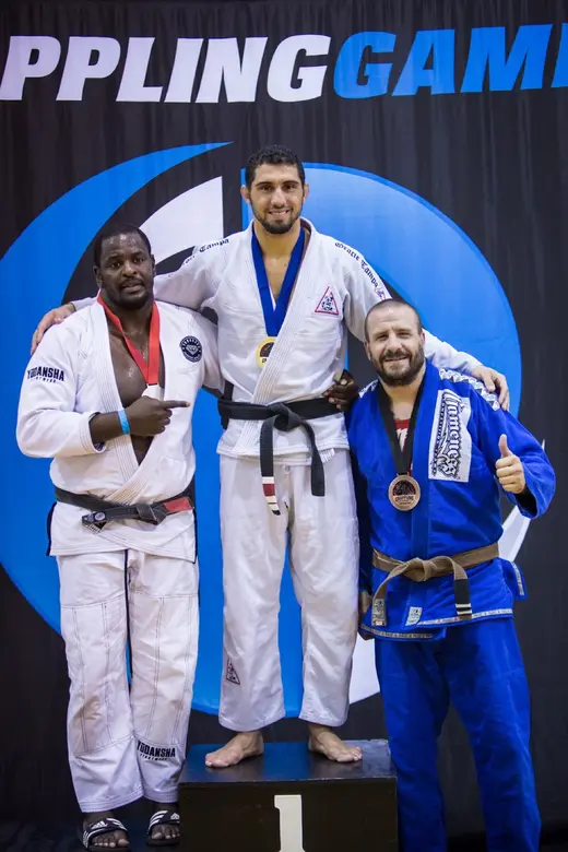 Sonny Parlin on the podium with a bronze medal at the Grappling Games, giving a thumbs up in a blue gi
